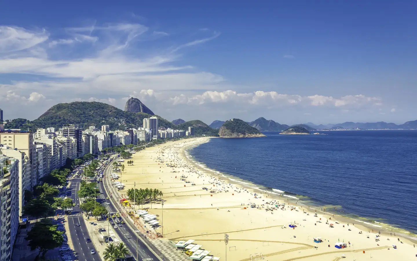 Aerial view of Copacabana beach curving along the coast with Sugarloaf Mountain in the distance, Rio de Janeiro, Brazil