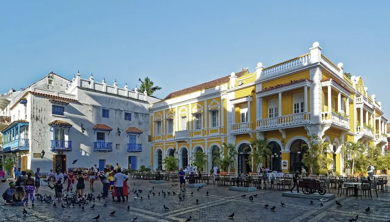 Colonial plaza with yellow buildings and people in the walled city of Cartagena, Colombia