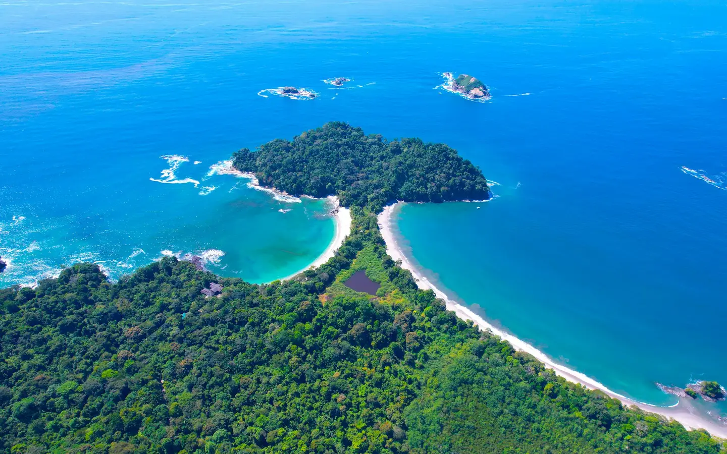 Aerial view of the forested Manuel Antonio headland between two crescent beaches and turquoise Pacific water, Costa Rica
