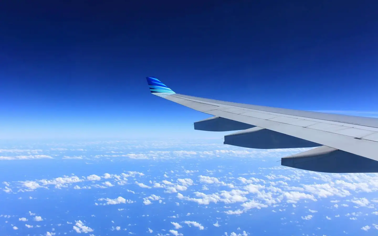 Airplane wing view above clouds — flights to Cuba from the UK