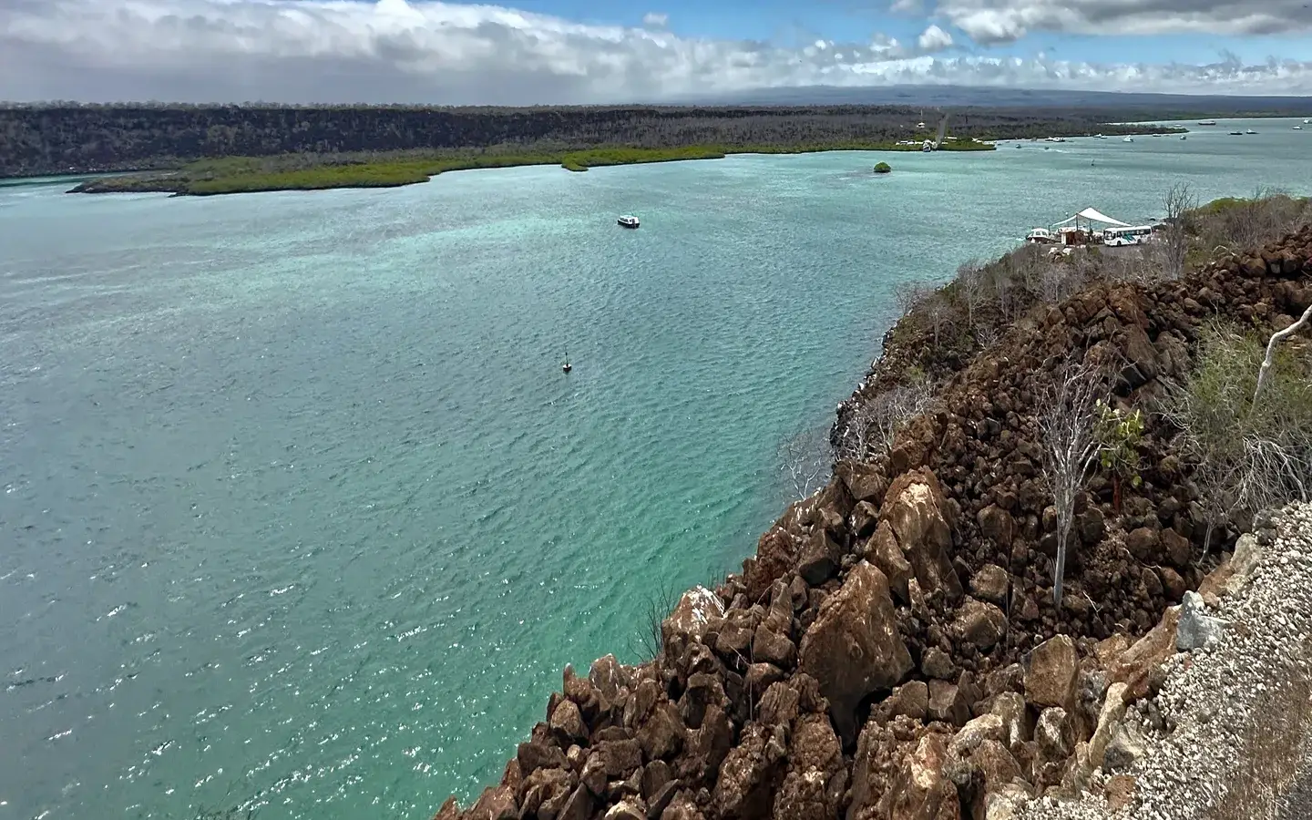 Turquoise channel and lava shoreline with a small boat at anchor, Santa Cruz island, Galápagos