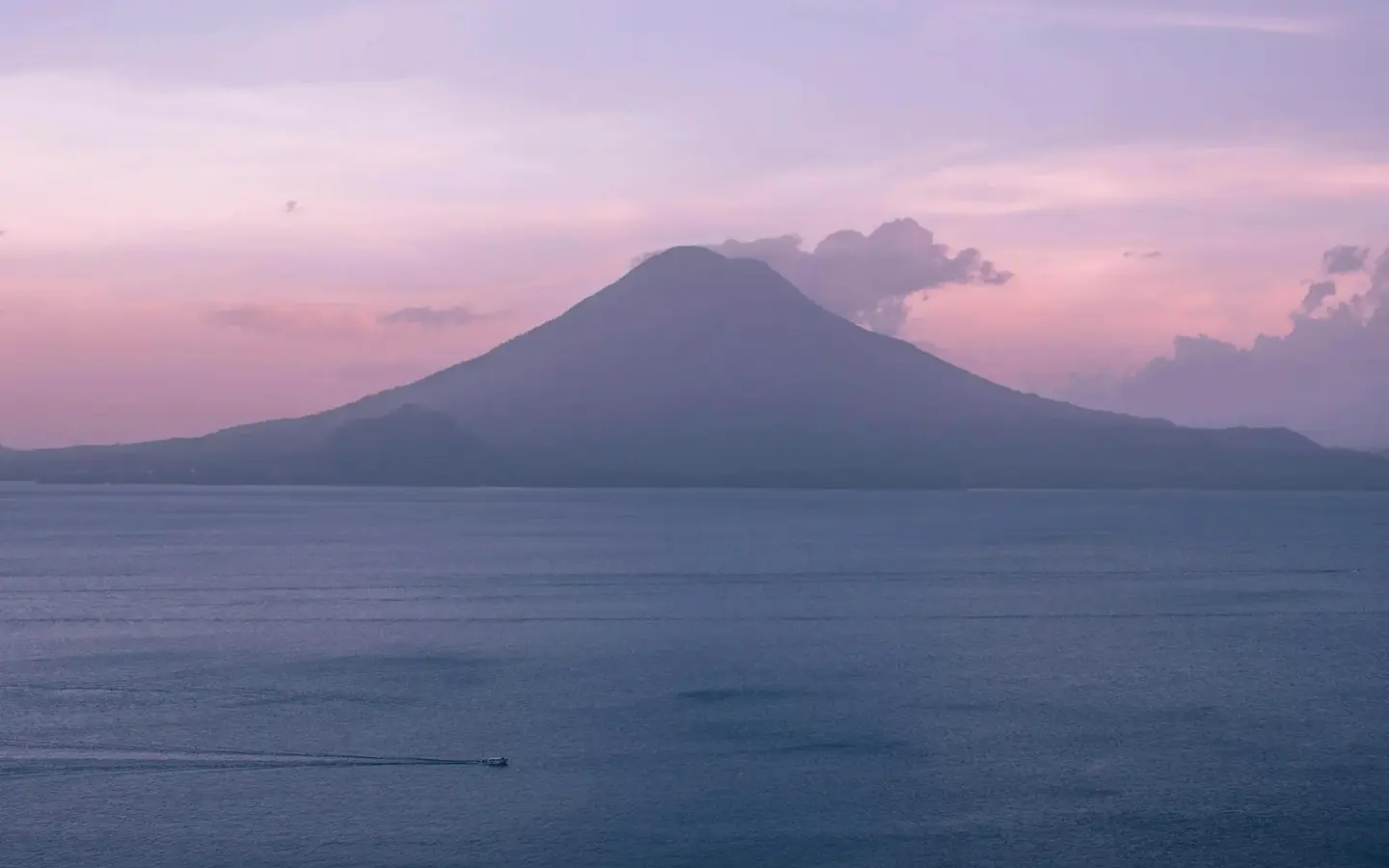 Lake Atitlan at sunset framed by volcanic peaks in Guatemala