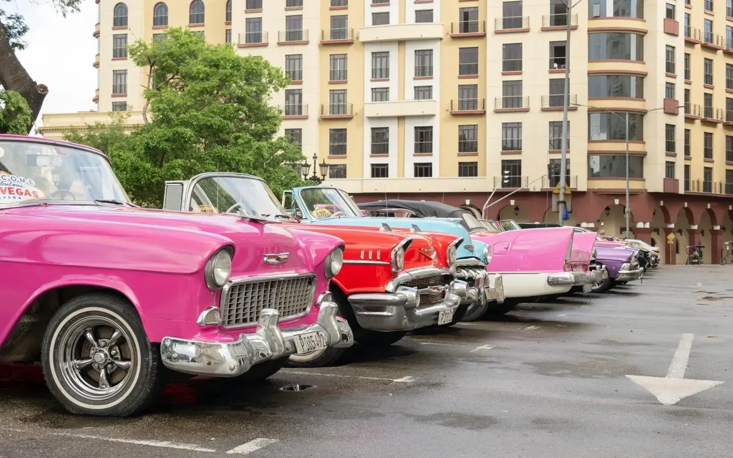 Colourful vintage American cars parked outside the Iberostar Grand Packard hotel in Havana, Cuba