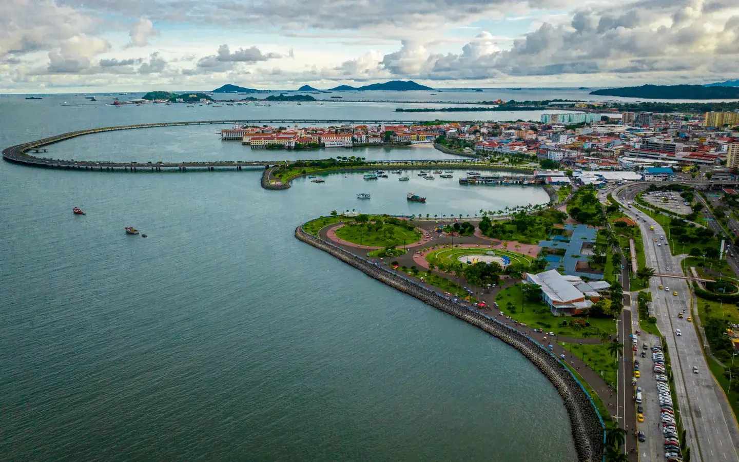 Aerial view of the Cinta Costera coastal loop curving past the red rooftops of Casco Viejo, Panama City