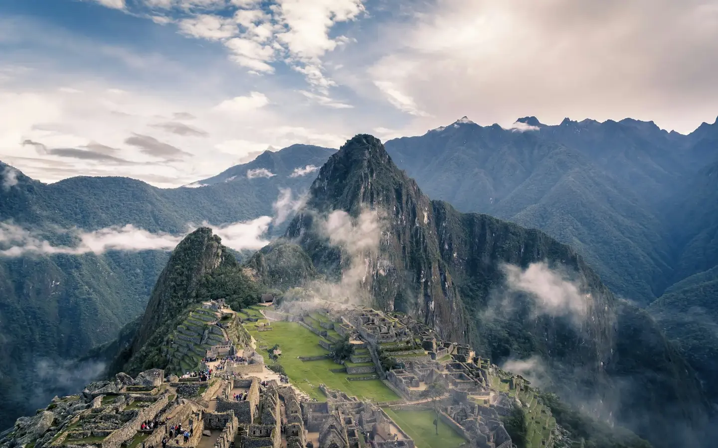 Hikers approaching the ancient Inca ruins of Machu Picchu along a mountain trail in Peru