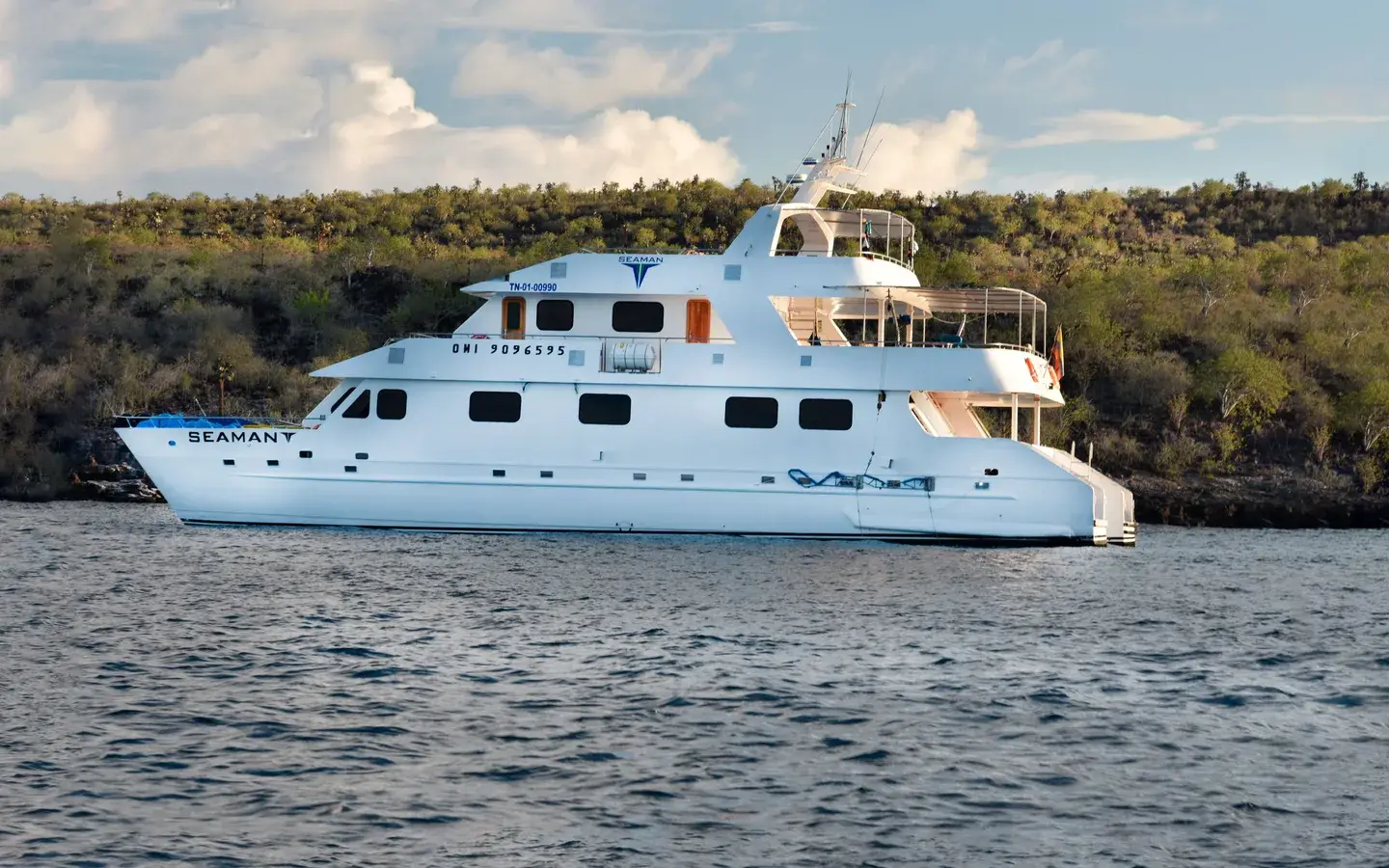 Seaman Journey catamaran anchored off a volcanic coastline, Galápagos