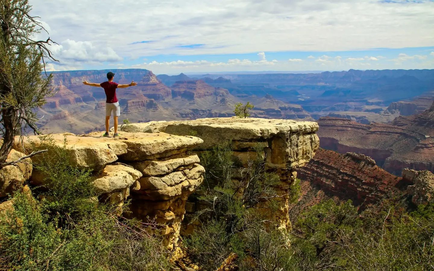 Hiker with outstretched arms overlooking the vast Grand Canyon at golden hour, Arizona, USA